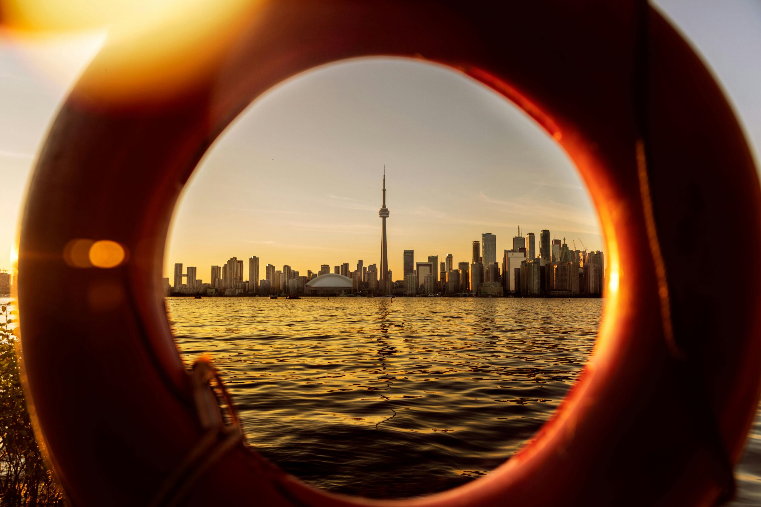 view of a toronto skyline at sunset framed through a lifebuoy ring