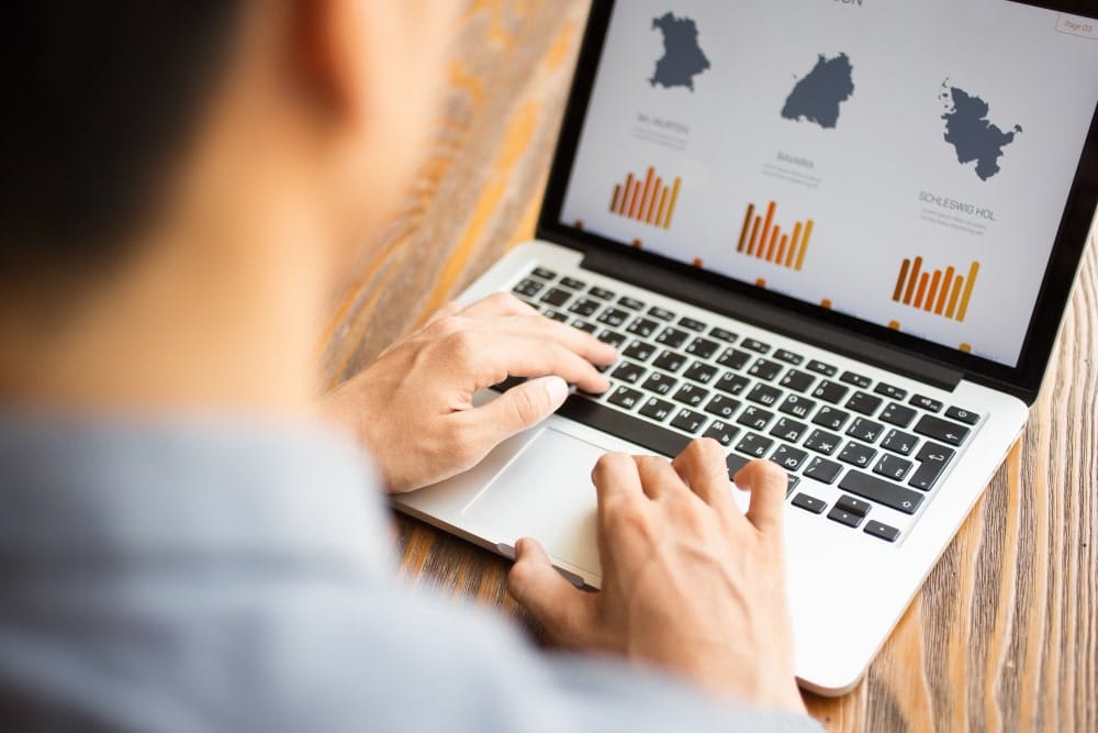 Man analyzing data charts on a laptop screen.