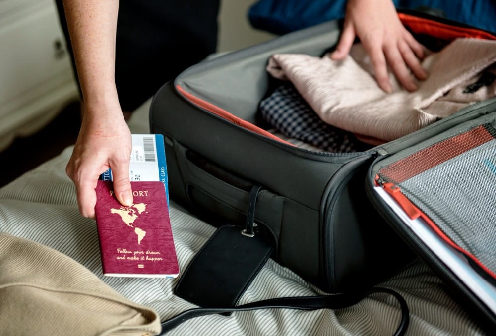 Traveler packing a suitcase with a Canadian-style passport and flight ticket