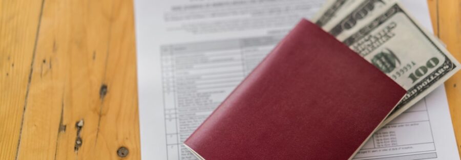 Passport with dollars on top of a travel insurance certificate.