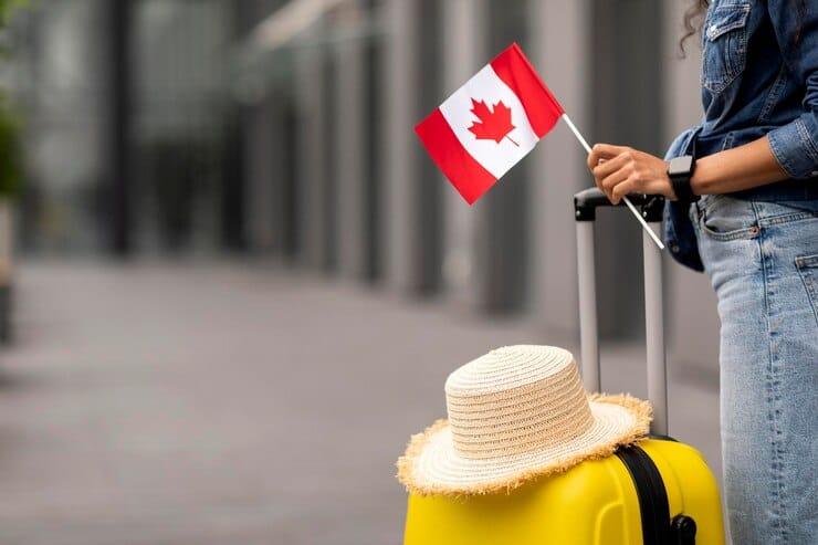 woman with suitcase holding canada flag arriving as newcomer