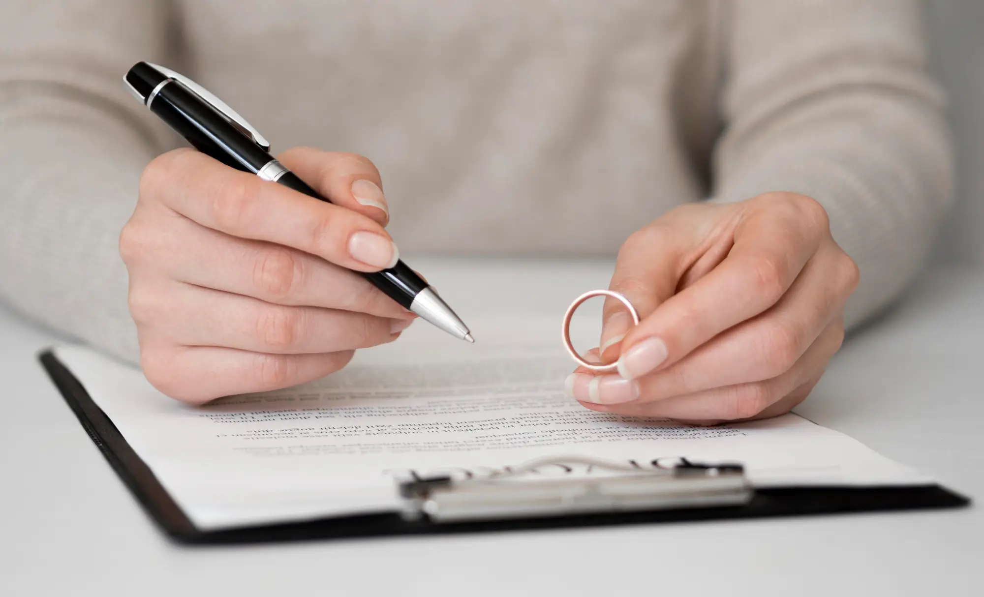 Hands holding a wedding ring and pen over a document – representing spousal sponsorship appeal process in Canada