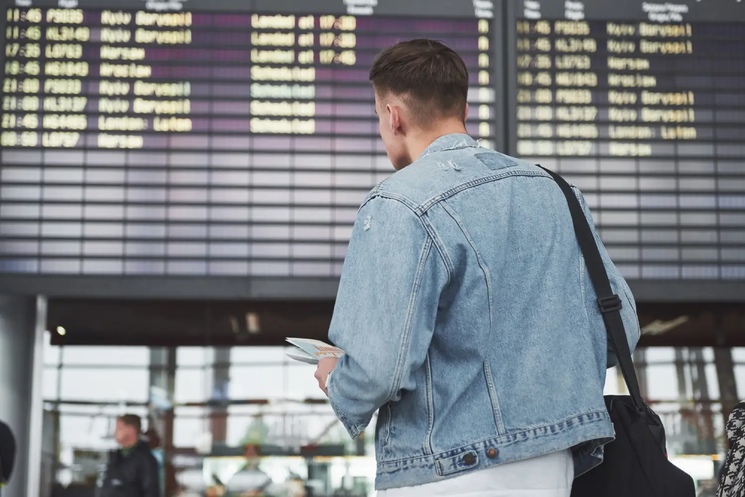Traveler at airport looking at flight information board before immigration entry