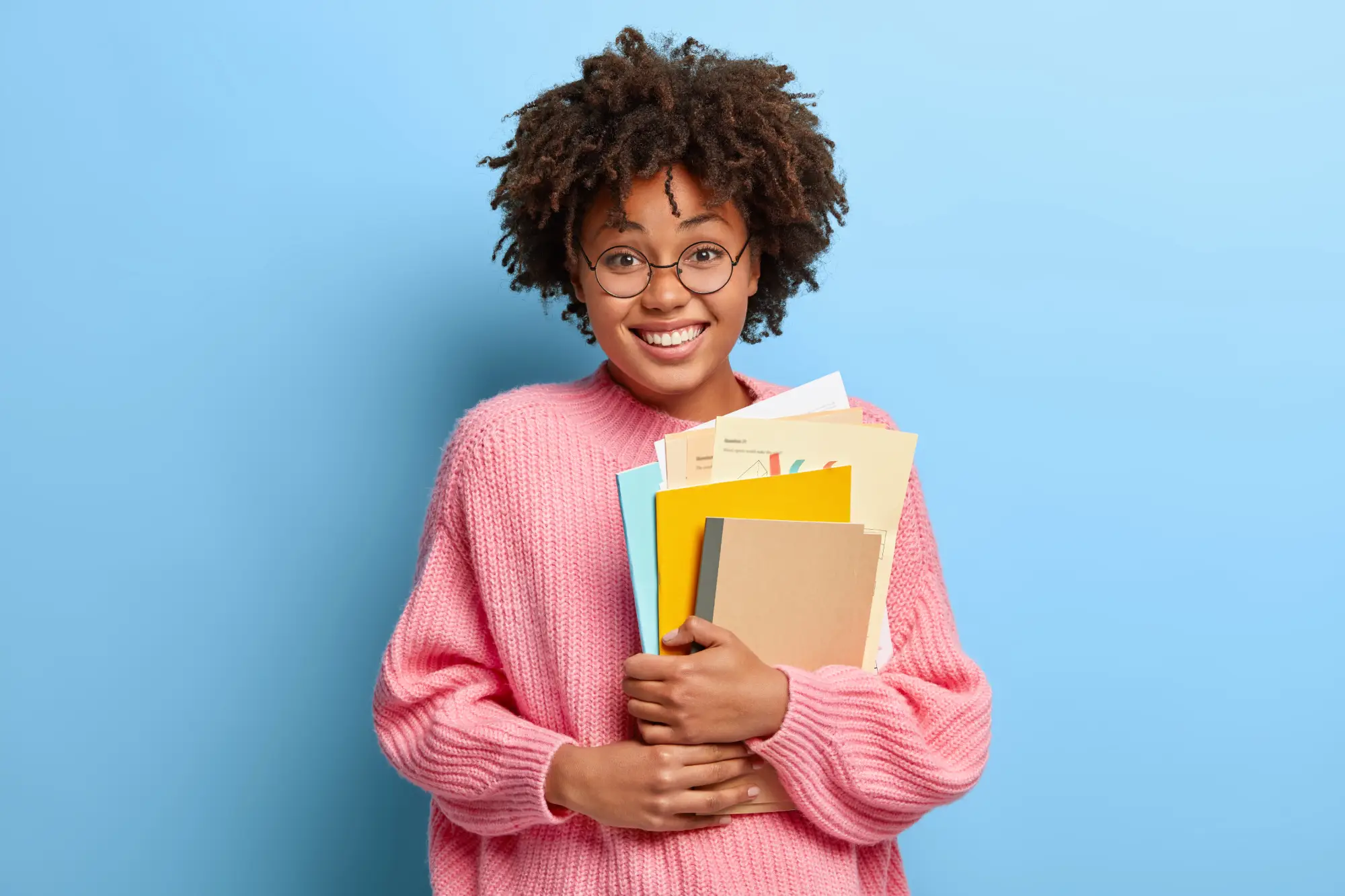Smiling student holding books and documents, representing changing Designated Learning Institution before arriving in Canada