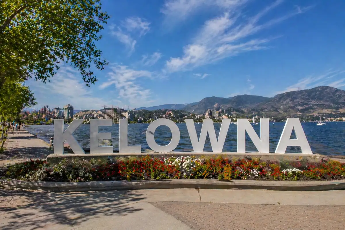 “Kelowna waterfront sign overlooking Okanagan Lake with city skyline and mountains in Kelowna”