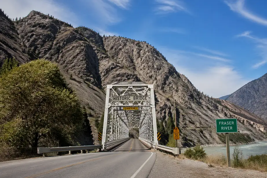 “Historic Fraser River bridge in Lytton surrounded by rugged mountains under a clear blue sky”