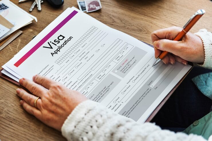 Person filling out a visa application form, symbolizing the start of the Express Entry application process for Canada.