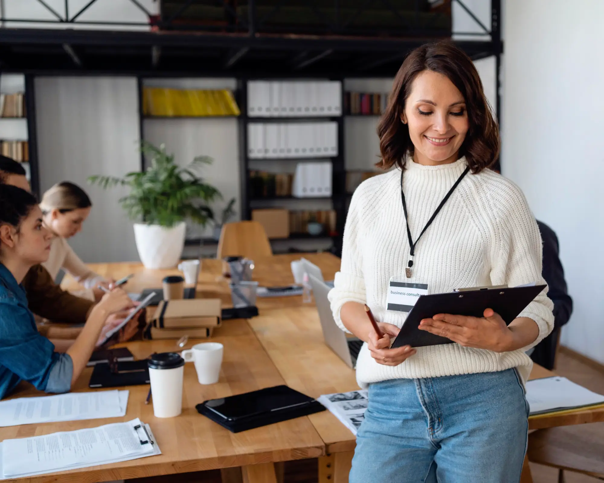 Woman holding clipboard and reviewing documents during a meeting, representing Labour Market Impact Assessment in Canada
