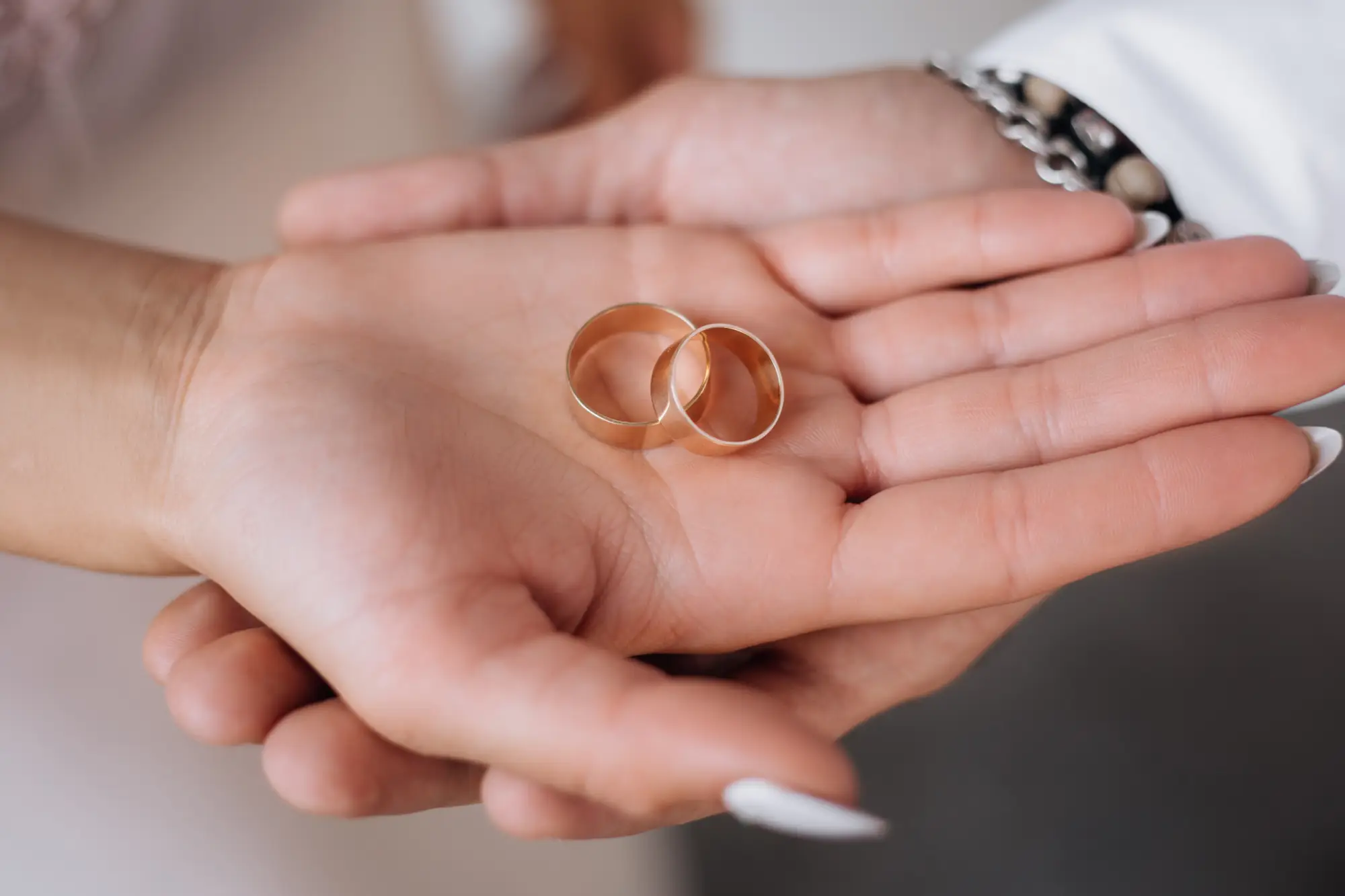 Two gold wedding rings in hand representing marriage and spousal sponsorship process in Ca
