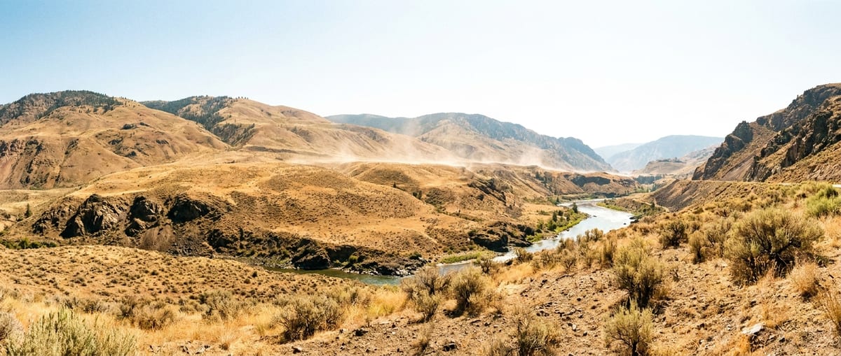 Photograph of the sun-scorched hills and winding river in Lytton, British Columbia, showcasing the arid landscape.